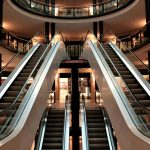 Symmetrical view of escalators in a modern shopping mall interior, showcasing architecture and design.