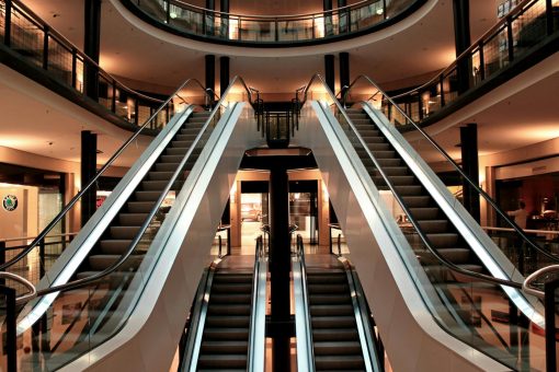 Symmetrical view of escalators in a modern shopping mall interior, showcasing architecture and design.
