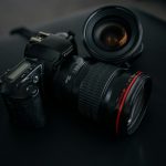 black Canon DSLR camera beside camera lens